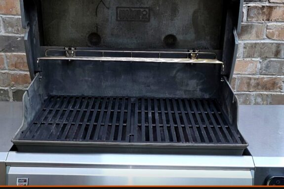 Weber gas grill with the lid open showing freshly cleaned cooking grates
