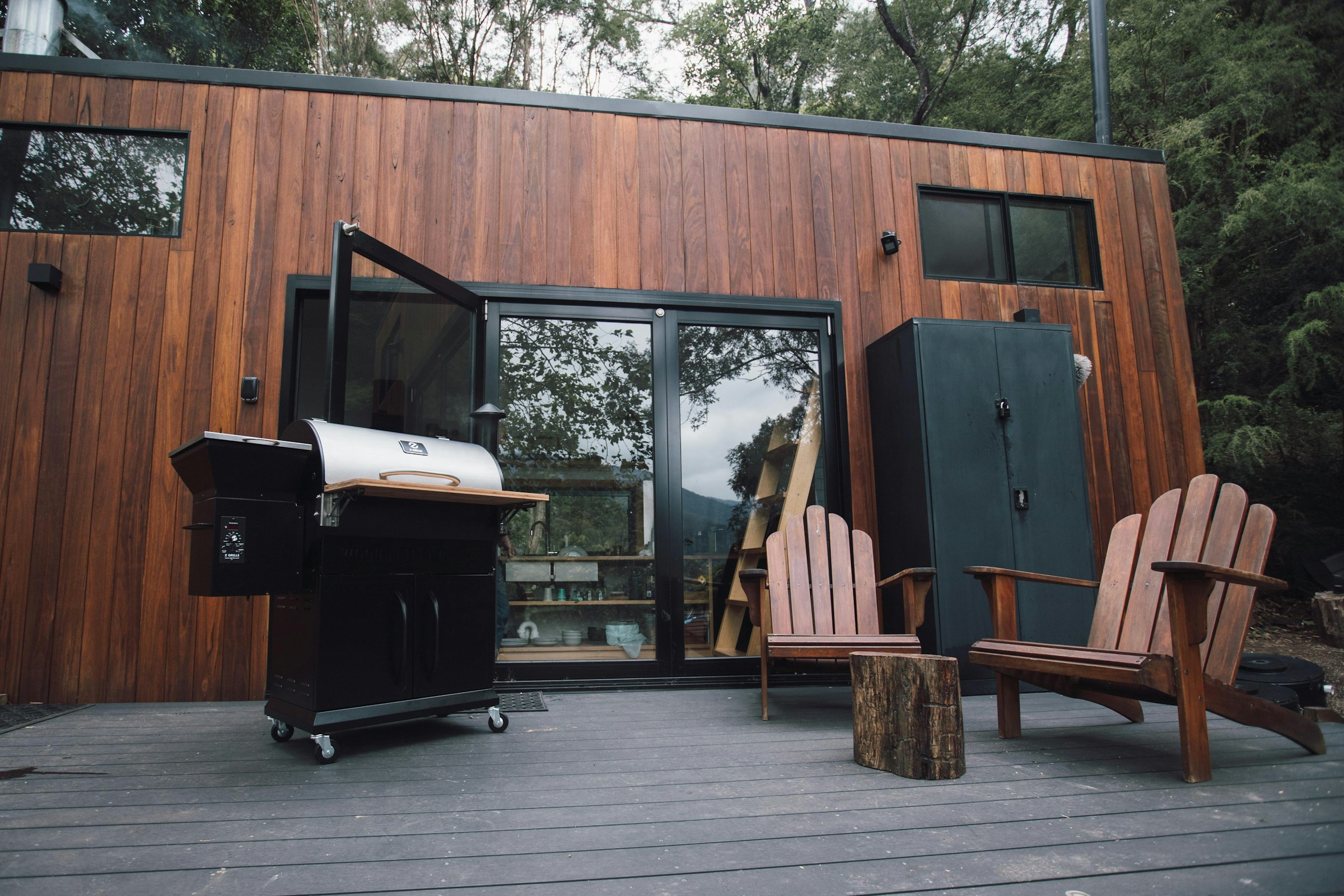 A black gas grill positioned outdoors on a patio beside a wooden wall