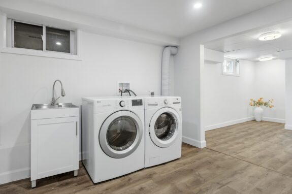 Modern laundry room with a front-load washer and dryer set against a grey wall