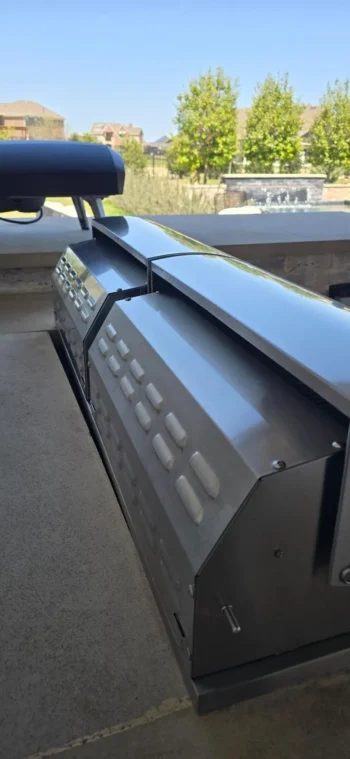 Polished stainless steel grill hood on a backyard outdoor kitchen after restoration