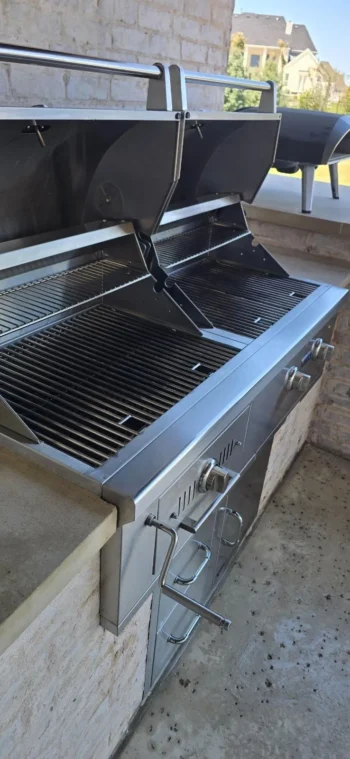 Built-in gas grill with hood open showing clean grates after professional grill cleaning